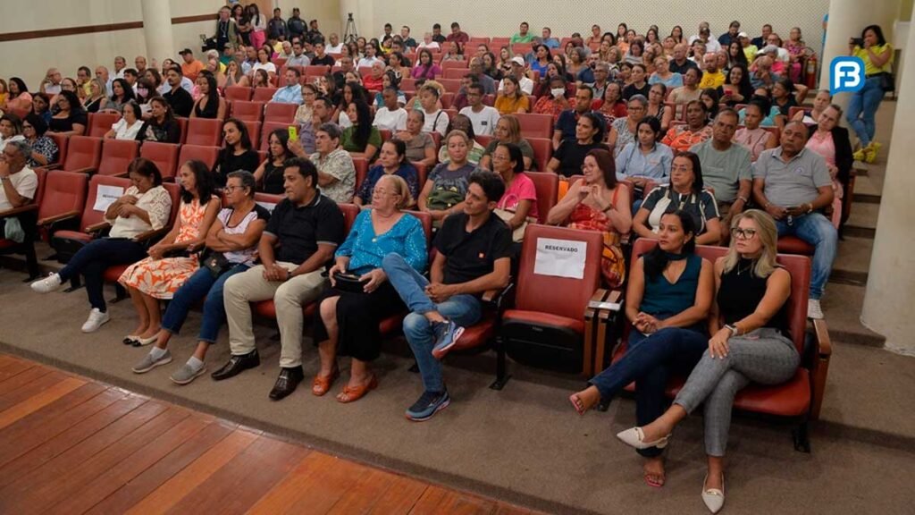 Moradores da "Rua de Cima" assistem atentos à cerimônia de entrega de matrículas do Projeto Morar Legal no Centro Cultural Rivelino Silva de Carvalho